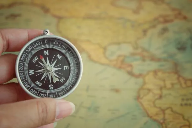 Woman hand holding a compass on map background